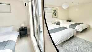 Ein modernes Hotelzimmer mit zwei Betten, einem Fenster, einem Deckenventilator und einem kleinen Nachttisch mit Lampe.