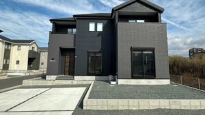 A modern two-story building with a flat roof, large windows, and a concrete foundation.