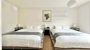 A hotel room with two beds, a bedside table with a lamp, a wall-mounted picture, and a ceiling light.