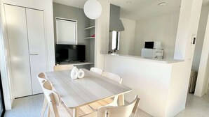 A modern kitchen with a dining area, white cabinetry, a central island, and a large window. - 10 mins to kumamoto airport Spacious 4BR House by Restavio (Ozu)