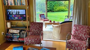 Un soggiorno con TV, librerie e due poltrone a fantasia.