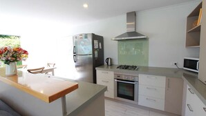 Una cocina moderna con horno empotrado, estufa a gas y refrigerador de acero inoxidable.