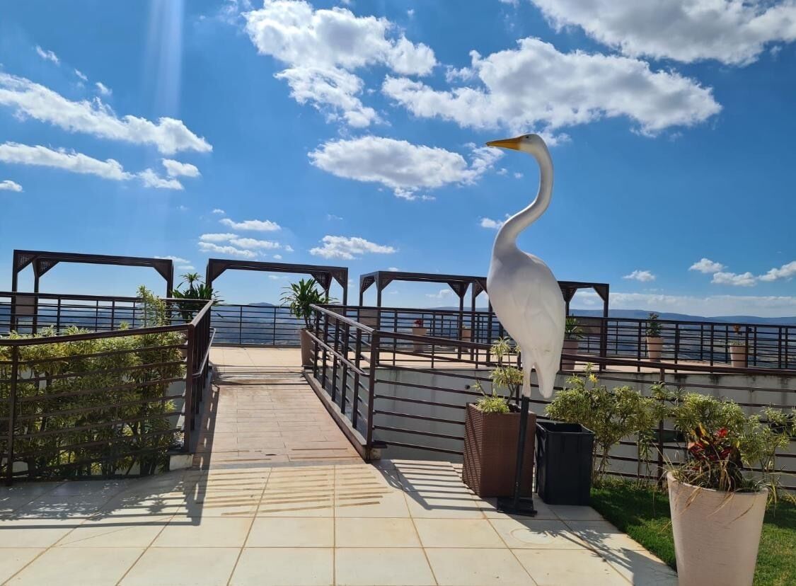 A walkway with a railing, potted plants, and a white bird statue.