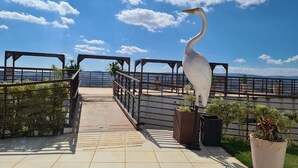 A walkway with a railing, potted plants, and a white bird statue. - Complete two-story house in Escarpas do Lago – Comfort and Leisure: Your Dream Retreat (Capitólio)