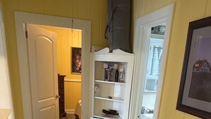 Ein Flur mit einem gemusterten Teppich, einem weißen Schrank mit Regalen und einer Tür zu einem weiteren Raum.