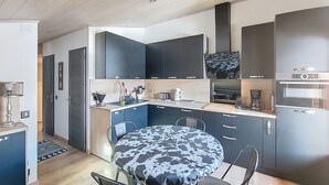 Moderni keittiö, jossa on tummat kaapit, sisäänrakennettu uuni ja kahvinkeitin.