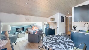 Ein moderner, kompakter Wohnraum mit Essbereich, Küchenzeile und einer gemütlichen Sitzecke mit Kamin.