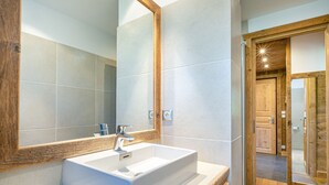 Ein modernes Badezimmer mit einem großen Spiegel, einem weißen Waschbecken und Holzelementen.