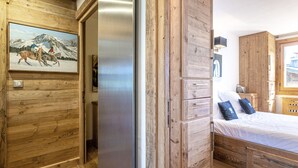 Ein Zimmer mit Holzwänden, einem Bett, einem Gemälde von Pferden und einem modernen Kühlschrank.