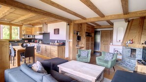 Ein rustikales Cabin-Interieur mit einem Essbereich aus Holz, einer Küche mit modernen Geräten, einem Kamin und einer gemütlichen Sitzecke mit Sofa und Sesseln.