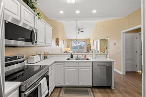 A modern kitchen with white cabinetry, stainless steel appliances, and a central island. - River Oaks Condo near beach & golf. Pool, tennis & free parking (Myrtle Beach)