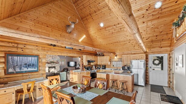 Interior de una cabaña de madera con comedor, cocina y chimenea.