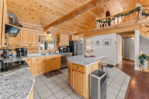 Una cocina amplia con gabinetes de madera, encimeras de granito y electrodomésticos de acero inoxidable.