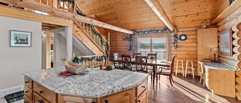 A wooden interior with a kitchen island, dining area, and a staircase.