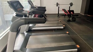 A gym with treadmills, a weight bench, and a rowing machine. - Lovely 2-bedroom in Nairobi near Yaya Centre — Everything Walkable (Nairobi)
