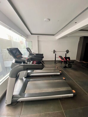 Ein Fitnessraum mit Laufbändern, einer Hantelbank und einem Rudergerät.