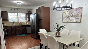Une cuisine moderne avec des meubles en bois, un réfrigérateur en acier inoxydable et un coin repas comprenant une table et des chaises.