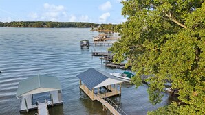 A lakeside dock with a covered boat launch area, a small pier, and a wooden dock extending into the water. - Tranquility on the Lake (Lake Norman of Catawba)