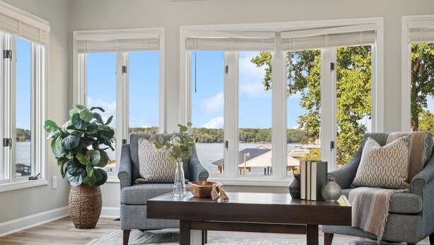A spacious living room with large windows, a comfortable sofa set, a coffee table, and a potted plant. - Tranquility on the Lake (Lake Norman of Catawba)
