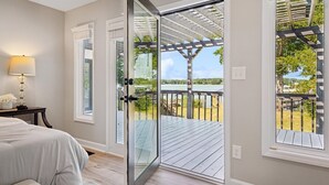A bedroom with a large sliding glass door leading to an outdoor deck with a pergola. - Tranquility on the Lake (Lake Norman of Catawba)