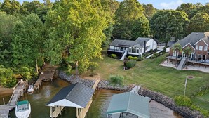 A lakeside property with a dock, a covered boathouse, and a house with a porch. - Tranquility on the Lake (Lake Norman of Catawba)
