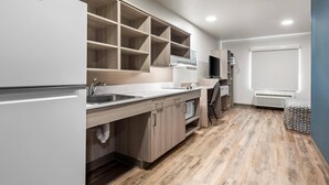 A modern kitchen with built-in cabinets, a refrigerator, and a sink. - Woodspring Suites Lancaster North (Lancaster)