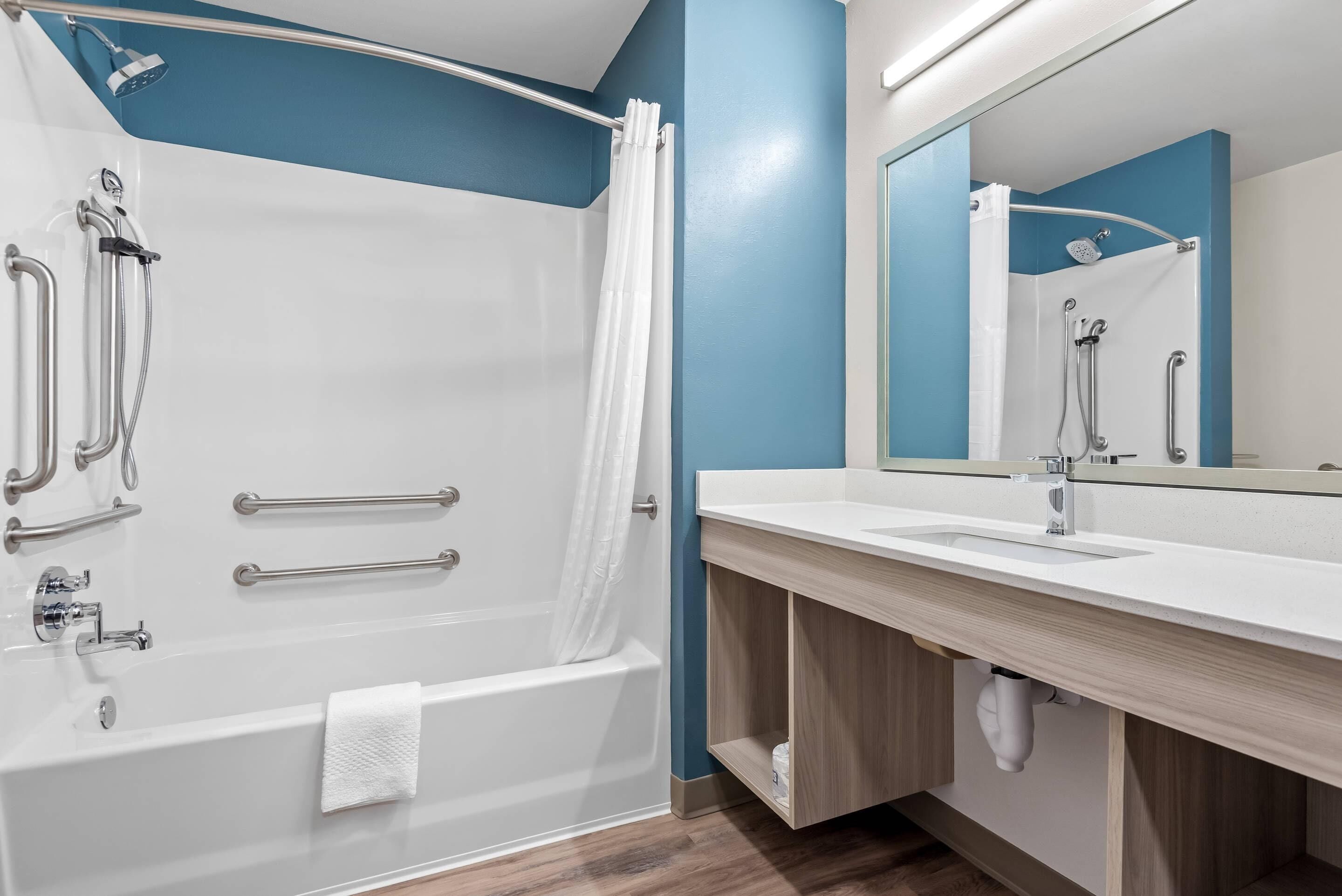 Une salle de bain moderne équipée d’une baignoire, d’une douche et d’un meuble-lavabo.