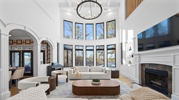 A spacious living room with a fireplace, large windows, and a piano. - Lake Norman Estate • Hot Tub + Fire Pit + Movie Theater | Lion Manor (Denver)