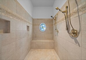 A shower with a golden showerhead and a circular window. - Lake Norman Estate • Hot Tub + Fire Pit + Movie Theater | Lion Manor (Denver)