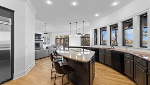 A modern kitchen with a central island, bar stools, and a built-in dishwasher. - Lake Norman Estate • Hot Tub + Fire Pit + Movie Theater | Lion Manor (Denver)