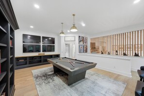 A modern living room with a pool table, bookshelves, artwork, and a wooden partition. - Spacious Lake Norman Home • Hot Tub + Firepit + Deck | Sleeps 22 | Lion Manor (Denver)