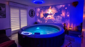 Une pièce avec un jacuzzi, une horloge murale, une cheminée et un ballon en forme de cœur.