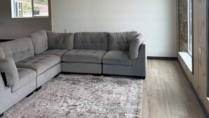 A modern living room with a sectional sofa, a patterned rug, and large windows. - The Lava White House - Sleeps 50+ (Lava Hot Springs)