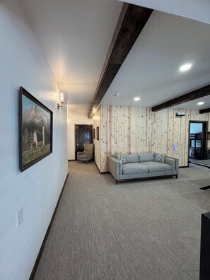 A modern interior with a grey sofa, wooden panel walls, and recessed ceiling lighting.