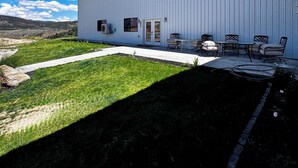 A large industrial building with a flat roof, a paved patio area with outdoor furniture, and a well-maintained lawn.