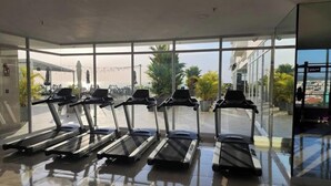 Un gimnasio con cintas de correr, ventanas amplias y vistas al exterior.