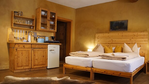 Une pièce chaleureuse avec un lit en bois, une petite kitchenette et un décor rustique.
