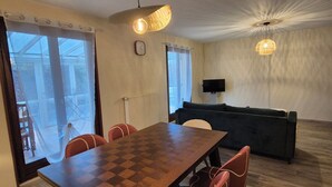 Ein Essbereich mit Holztisch und Stühlen, einer Couch und zwei Pendelleuchten.