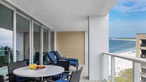Un balcón con una mesa lista para el desayuno, con vista a una playa.
