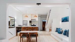 A modern kitchen with a dining area, white walls, and a staircase leading to another level. - Town House 4: Comfort and golf course view (Hacienda Iguana)
