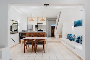 A modern kitchen with a dining area, white walls, and a staircase leading to another level. - Town House 4: Comfort and golf course view (Hacienda Iguana)