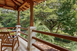A wooden deck with a tiled floor, surrounded by lush greenery and trees.