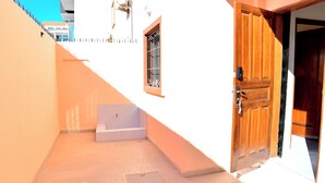 A narrow alleyway with a white building, a wooden door, and a window with bars. - MAGNIFICENT FURNISHED VILLA, TEMPORARY RENTAL, CITE ALiou Sow Golf Sud (Dakar)