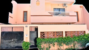 A two-story building with a flat roof, a balcony on the upper floor, and a gated entrance with a small garden in front. - MAGNIFICENT FURNISHED VILLA, TEMPORARY RENTAL, CITE ALiou Sow Golf Sud (Dakar)