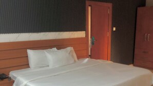 Un dormitorio con una cama grande, cabecera de madera, una mesita de noche con un teléfono y un armario.