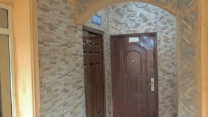 Zona de recepción con un cartel sobre una puerta, una ventana a la izquierda y una pared con textura.