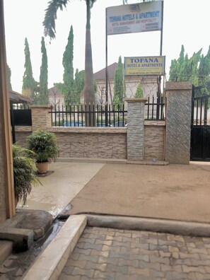 A gated entrance to a hotel with a stone wall and a sign for Tofana Hotel & Apartments. - Tofana hotels and apartments Life camp (Abuja)