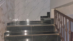 Una escalera con escalones de mármol negro y barandilla de madera.