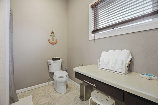 Un baño con inodoro, lavamanos y toallero, y una zona de ducha.