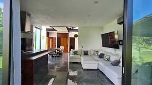 A modern living room with a white sofa, a dining area with a table and chairs, and a kitchen with a stove and cabinets. - Residence near the beach (Mezcales)